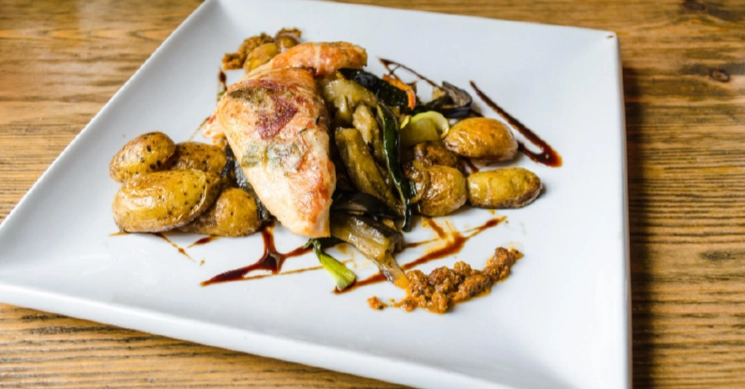 A small plate of grilled chicken, olives, and crispy toppings served over a creamy base, perfect for cocktail-style wedding receptions.