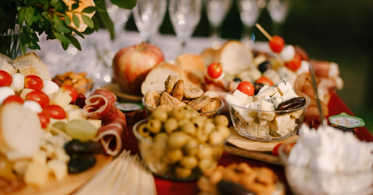 A beautifully arranged charcuterie-style appetizer spread featuring cheeses, olives, bread slices, tomatoes, and fresh fruits, styled for an elegant wedding reception.