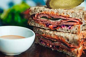 a cold cut sandwich cut in half with soup from a catering menu